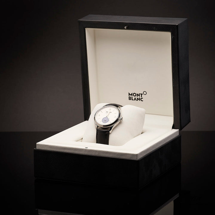 Armbanduhr mit weißem Ziffernblatt und schwarzem Armband in Originalbox vor dunkelgrauem Hintergrund