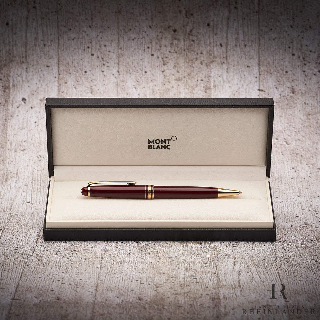 Roter Drehbleistift mit goldenen Beschlägen in Originalbox liegend vor grauem Hintergrund