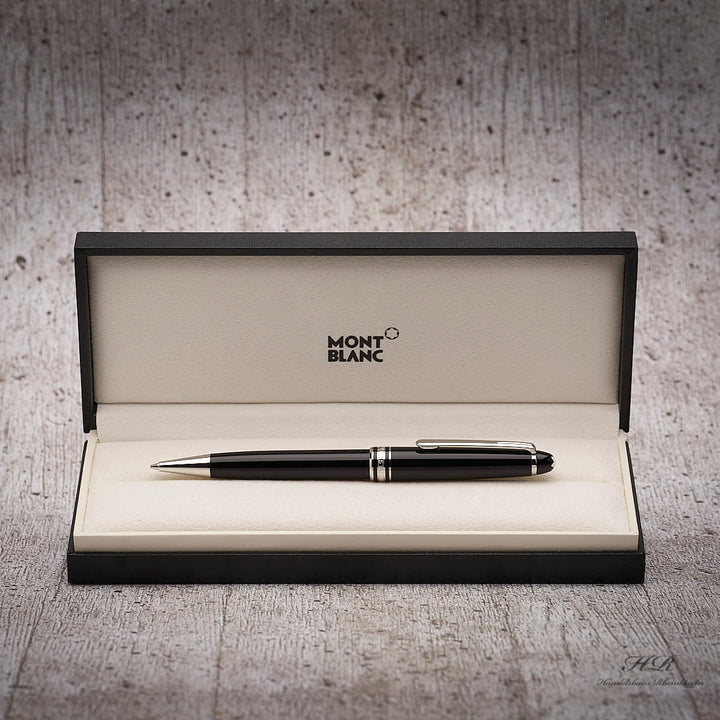 Schwarzer Drehbleistift in Originalbox liegend vor grauem Hintergrund in Holzoptik