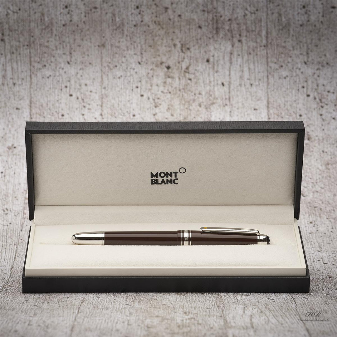 Dunkelbrauner Füller in geöffneter Originalbox liegend vor grauem Hintergrund in Holzoptik