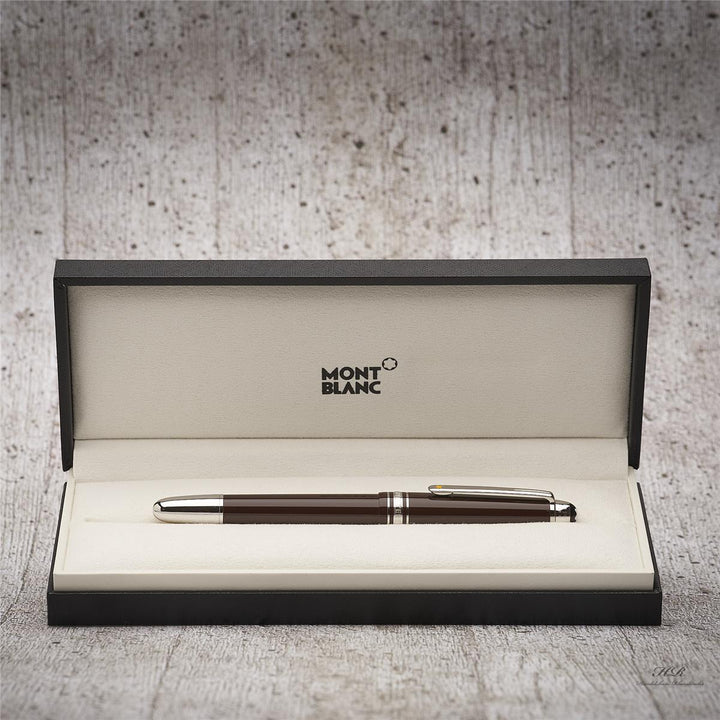 Dunkelbrauner Füller in geöffneter Originalbox liegend vor grauem Hintergrund in Holzoptik