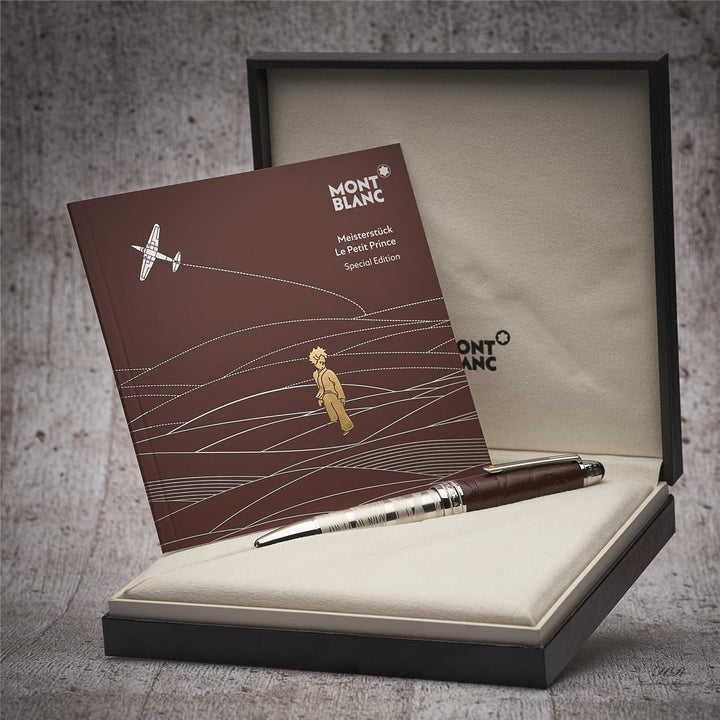 Silberner Rollerball mit dunkelbrauner Kappe in Originalbox liegend, daneben Serviceheft mit Grafikdruck