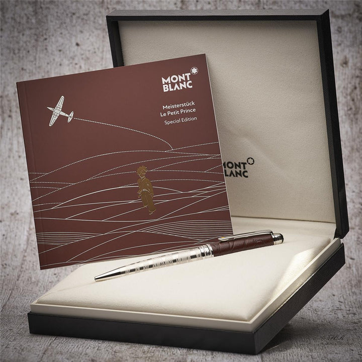 Silberner Kugelschreiber mit dunkelbrauner Kappe in Originalbox liegend, daneben Serviceheft mit Grafikdruck