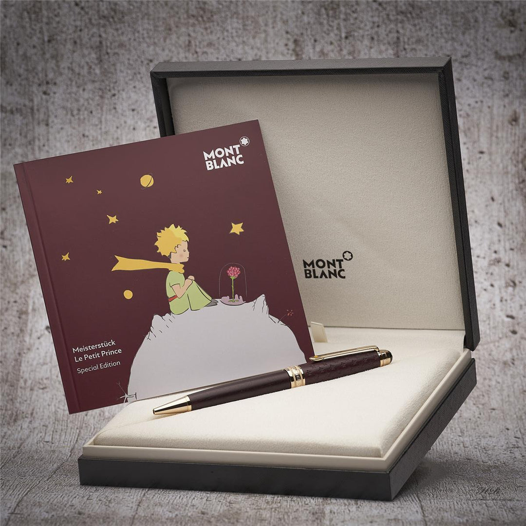 Burgunderfarbener Kugelschreiber in Originalbox liegend, daneben Serviceheft mit Grafikdruck, Hintergrund grau