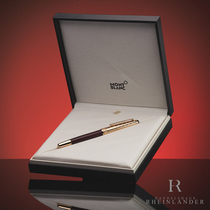Burgunderfarbener Rollerball mit goldener Kappe liegt in Originalbox vor rotem Hintergrund