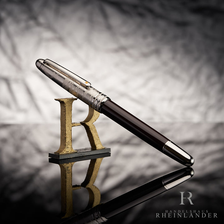 Dunkelbrauner Rollerball mit silberner Kappe an 3D-Buchstabe R lehnend vor grauem Hintergrund