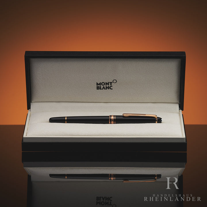 Schwarzer Rollerball mit rotgoldenen Beschlägen in offener Originalbox liegend vor orangebraunem Hintergrund