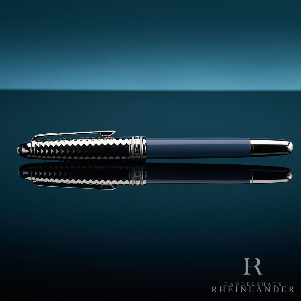 Blauer Rollerball mit geometrisch gemusterter, silberner Kappe vor blauem Hintergrund liegend