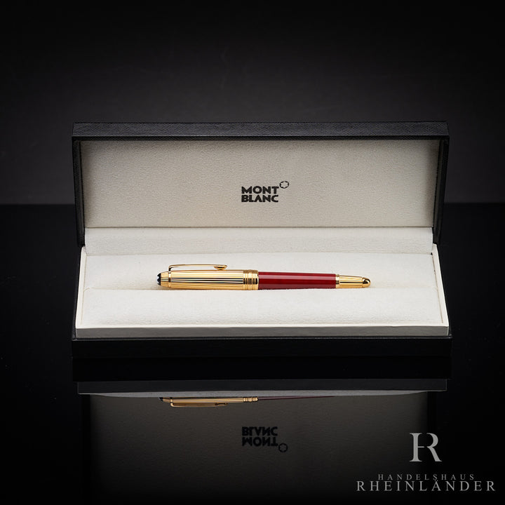 Roter Füller mit goldener Kappe in offener Originalbox liegend vor schwarzem Hintergrund