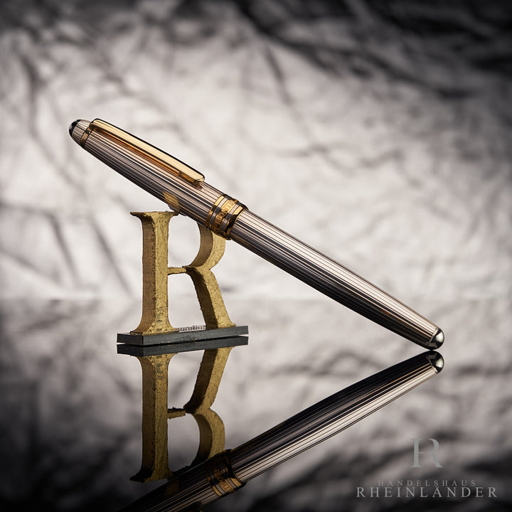 Slberner Rollerball an 3D-Buchstabe R lehnend vor grauem Hintergrund