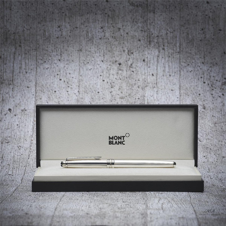 Silbernes Schreibgerät frontal in offener Montblanc-Box liegend fotografiert, Hintergrund hellgrau mit Holzoptik