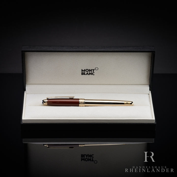 Goldener Füller mit roter Kappe in offener Originalbox liegend vor schwarzem Hintergrund fotografiert