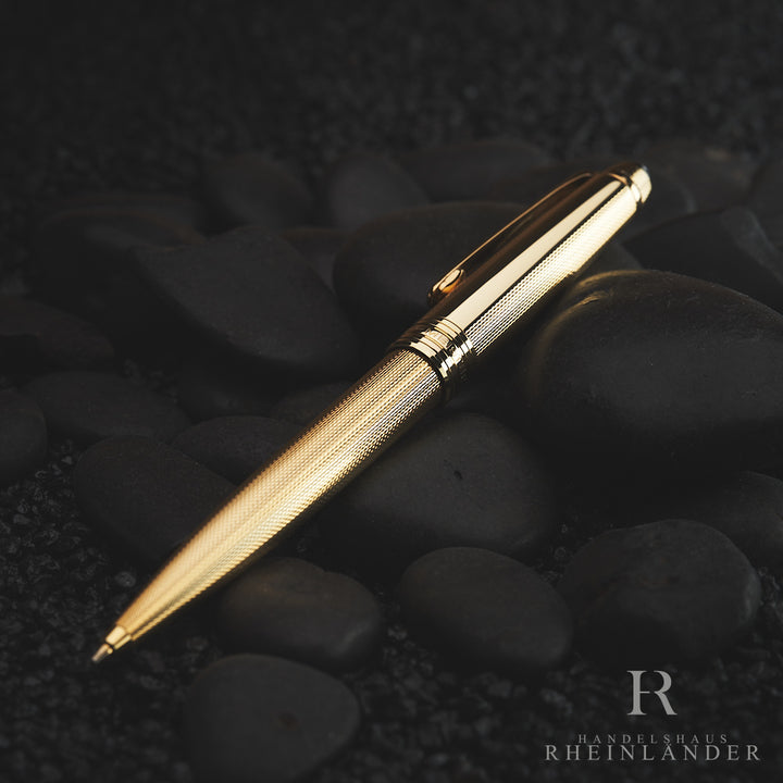Goldener Bleistift von schräg oben auf dunkelgrauen, edlen Dekorsteinen liegend fotografiert