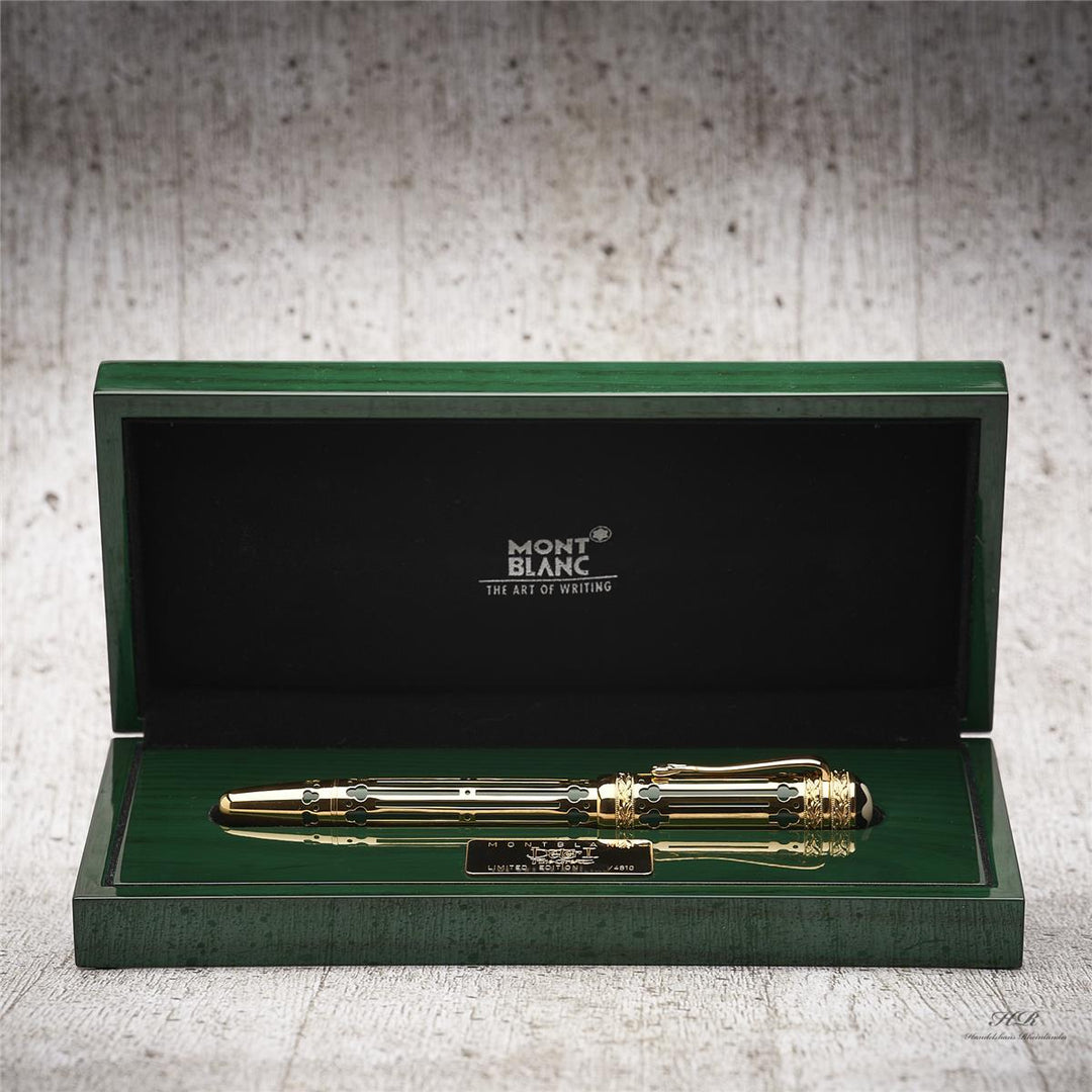 Grün-goldener Füller liegt in offener, grün lackierter Holzbox vor hellgrauem Holzoptik-Hintergrund