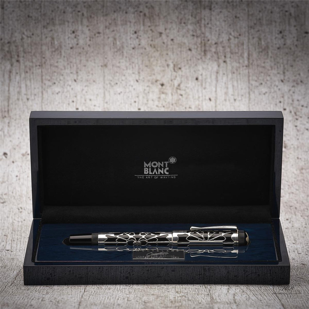 Silber-schwarzer Füller liegt in offener Originalbox vor grauem Hintergrund in Holzoptik