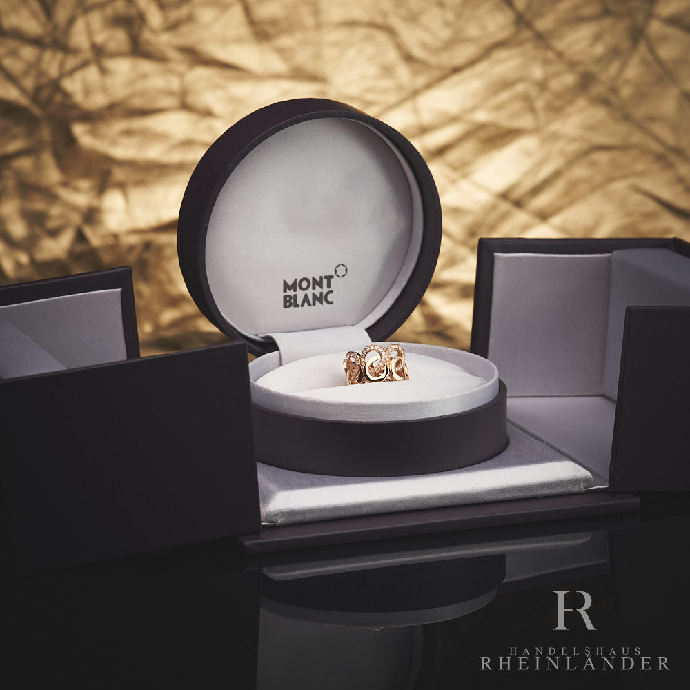 Goldener Ring mit Schleifenstruktur und Diamantbesatz in offener Originalbox vor goldenem Hintergrund