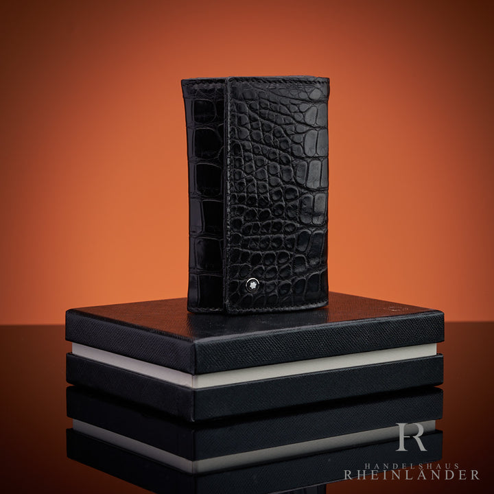 Schlüsseletui aus schwarzem Alligatorleder auf Montblanc-Geschenkbox vor orangem Hintergrund