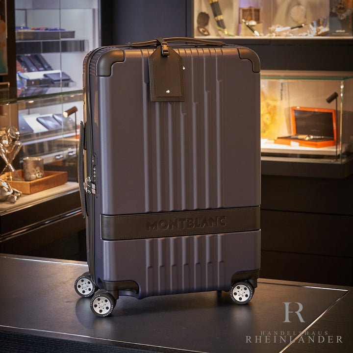 grauer Montblanc Hardshell Trolley mit Rollen auf schwarzem Tisch