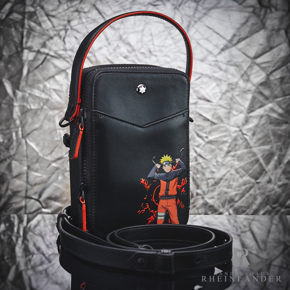 Schwarz-orange Naruto Tasche mit Handriemen steht hinter gerolltem Schulterriemen