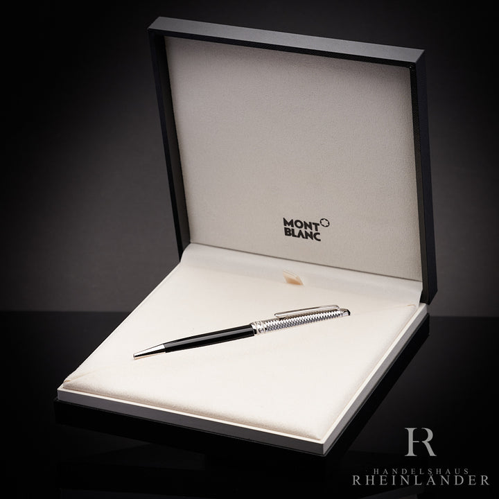 Zweifarbiger Kugelschreiber in Textilbett der offenen Originalbox liegend fotografiert, Hintergrund schwarz grau