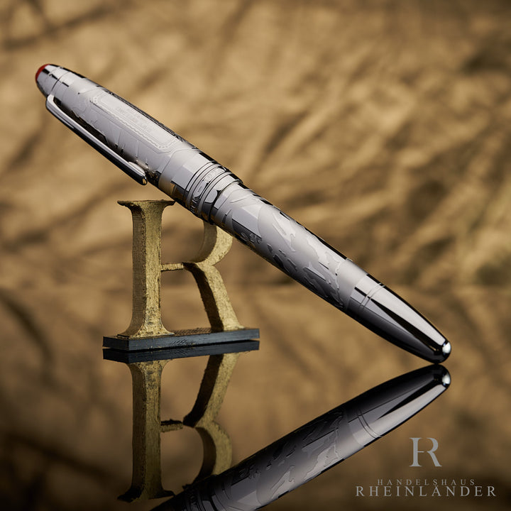 Silberner Rollerball von Montblanc mit silbernen Details vor beige-goldenem Hintergrund auf Halter lehnend