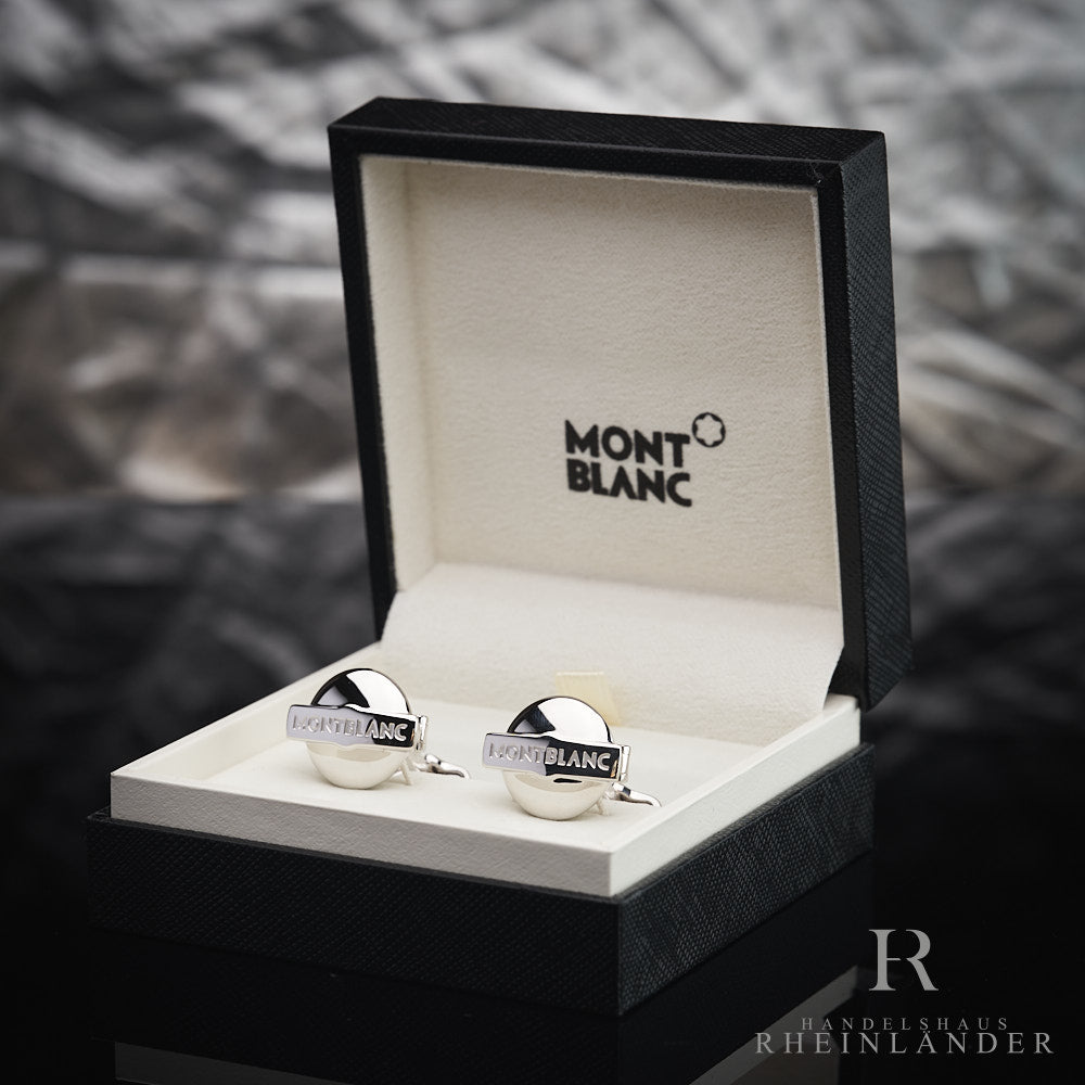 Runde, silberne Manschettenknöpfe mit Montblanc-Schriftzug in Originalbox vor silbergrauem Hintergrund