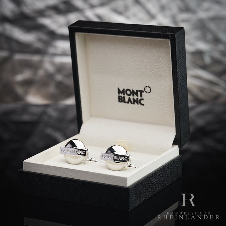 Runde, silberne Manschettenknöpfe mit Montblanc-Schriftzug in Originalbox vor silbergrauem Hintergrund