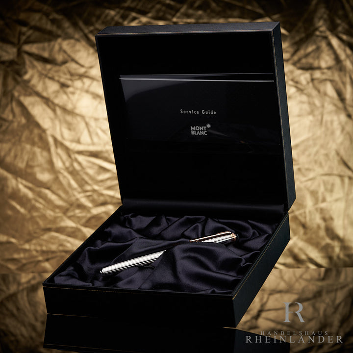 Silberner Rollerball von Montblanc in schwarzer Montblanc-Box mit Serviceheft vor goldenem Hintergrund fotografiert