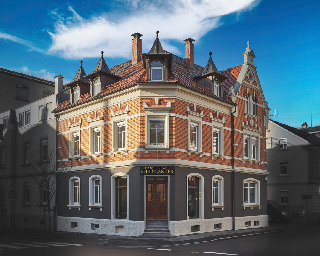 Außenansicht des Handelshaus Rheinländer mit historischem Gebäude bei Sonnenschein und blauem Himmel
