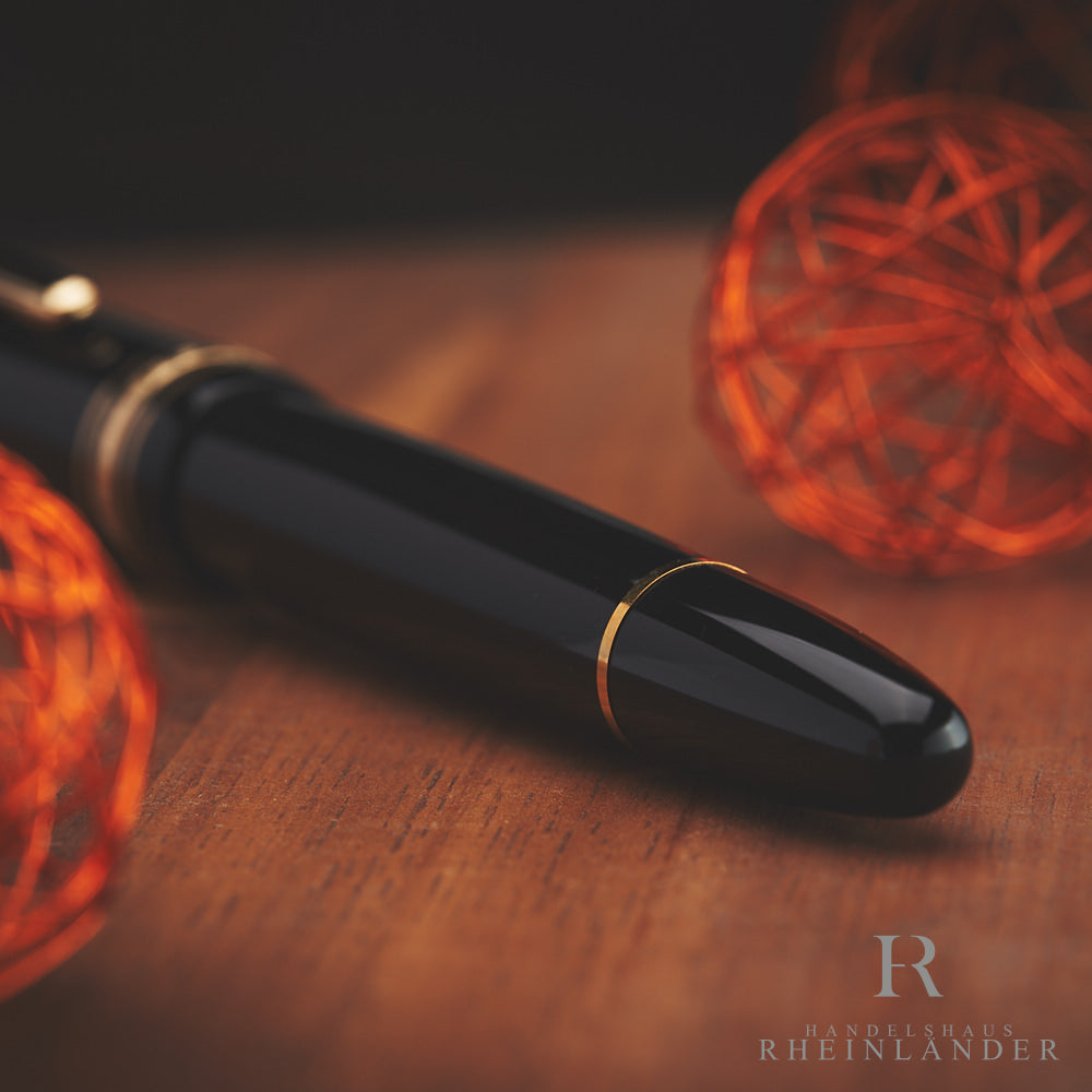 Konusende des Montblanc Anniversary Füllers auf Holztisch mit orangenen Dekoartikeln