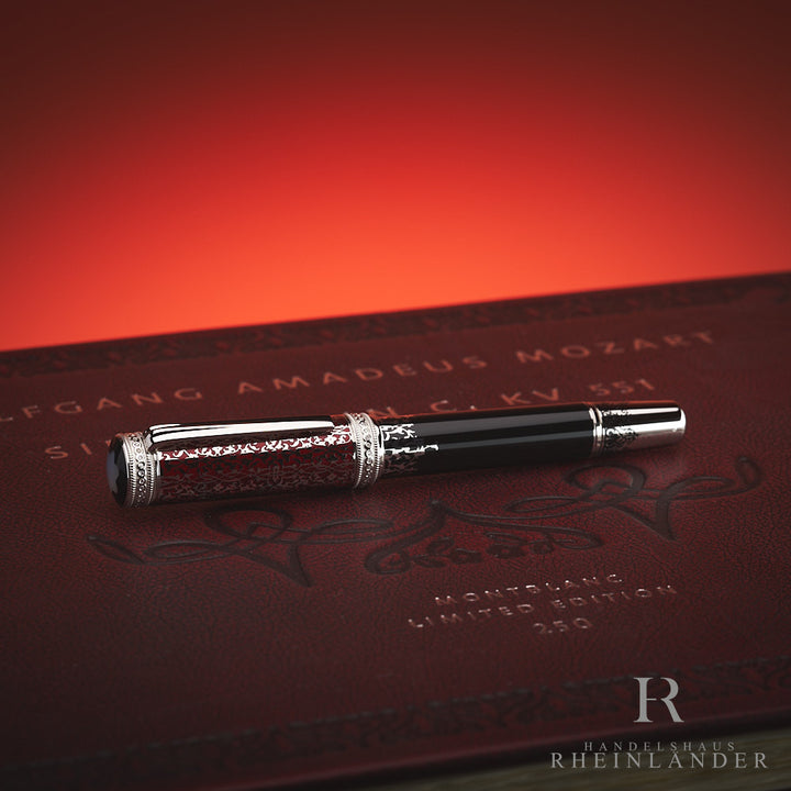 Schwarzer Montblanc Füller mit aufwendigen Details liegt auf Mozart-Editionsbox, nah von oben vor rotem Hintergrund fotografiert
