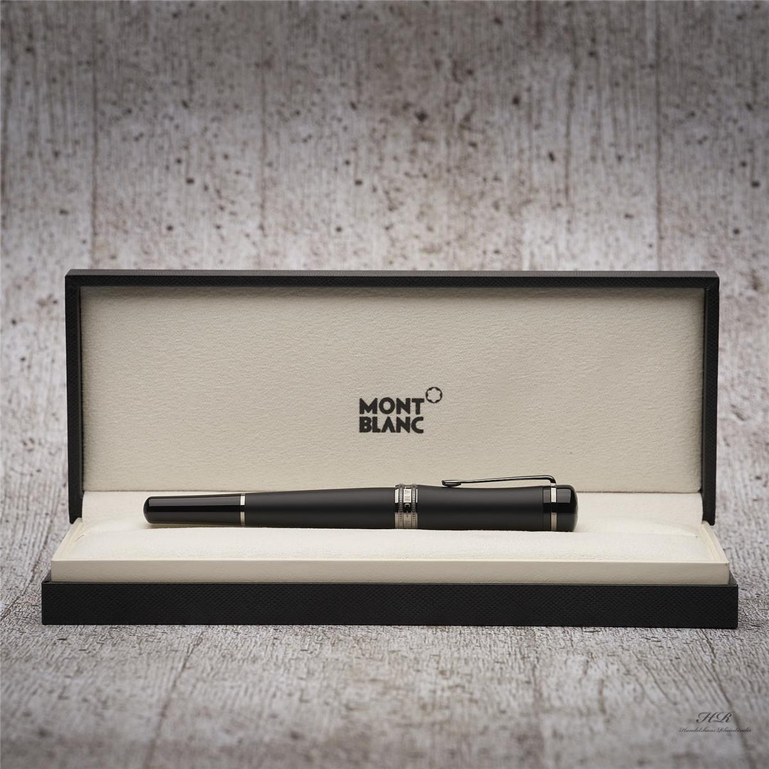 Schwarzer Montblanc Rollerball liegt in offener Originalbox vor grauem Hintergrund in Holzoptik
