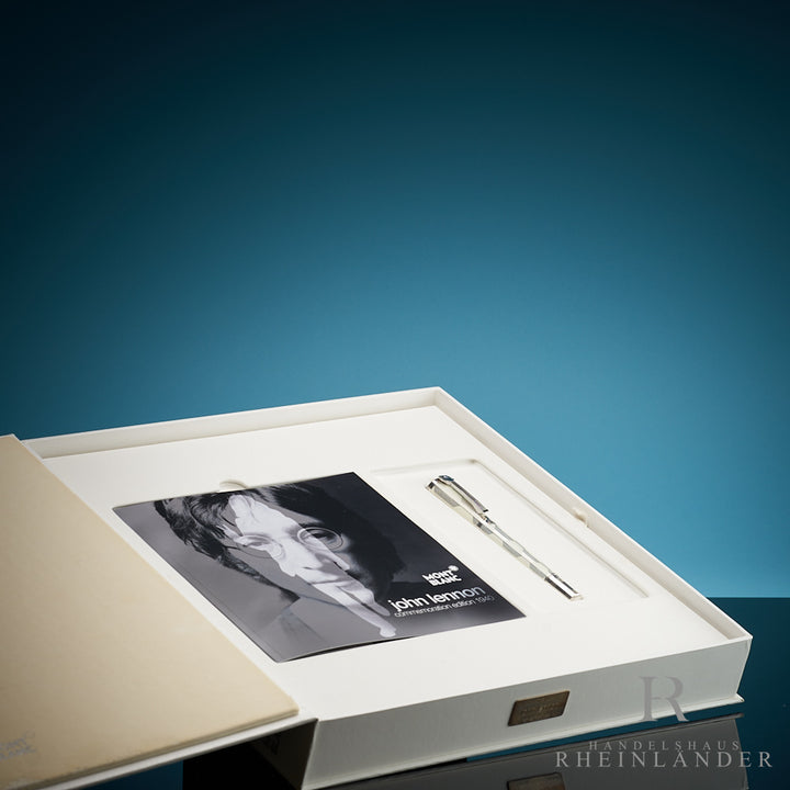 Silberner Füller zusammen mit John Lennon Serviceheft in weisser Originalbox liegend vor blauem Hintergrund