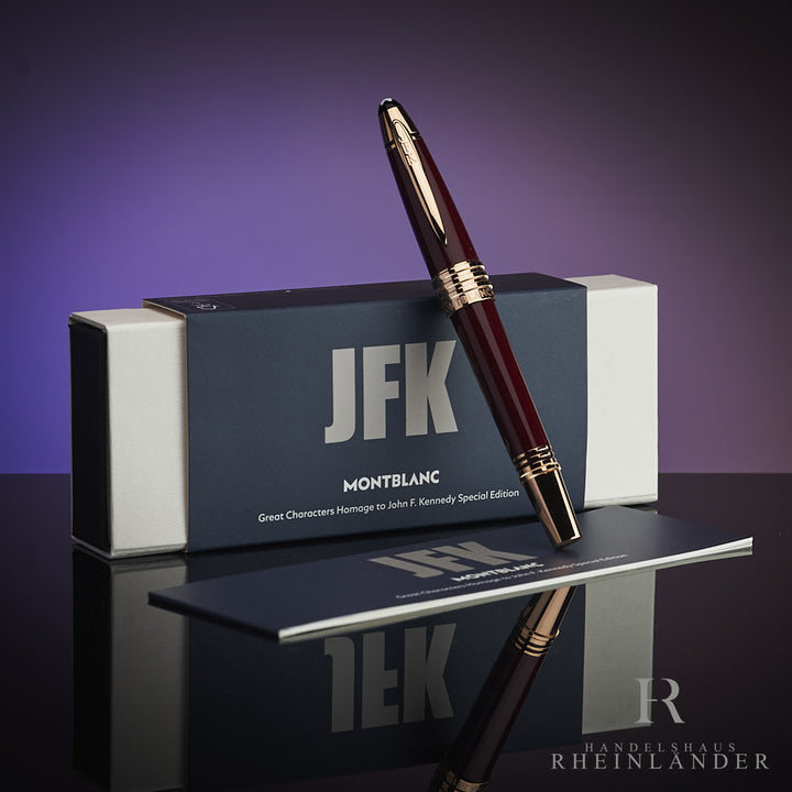 Dunkelroter Rollerball lehnt an Originalbox mit JFK-Schriftzug. Unter dem Stift das Serviceheft, Hintergrund lila.
