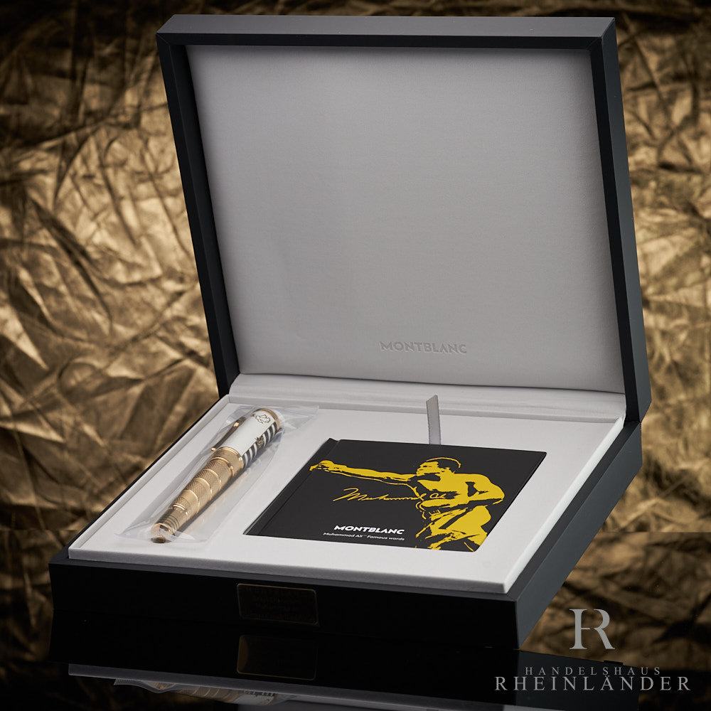 Gold-weisser Füller liegt zusammen mit Serviceguide in offener Originalbox vor goldenem Knitteroptik-Hintergrund