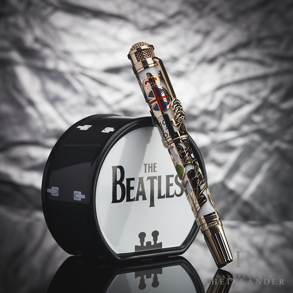 Mehrfarbiger Füller lehnt an kleiner, schwarz-weißer Trommel mit Beatles-Schriftzug vor silbergrauem Hintergrund