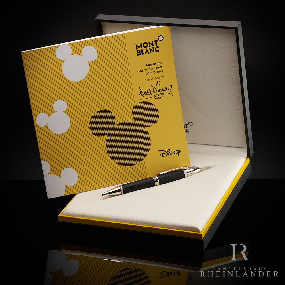 Schwarzer Kuli liegt in offener Editionsbox. Darin aufgestellt das gelbe Disney-Serviceheft. Hintergrund dunkelgrau
