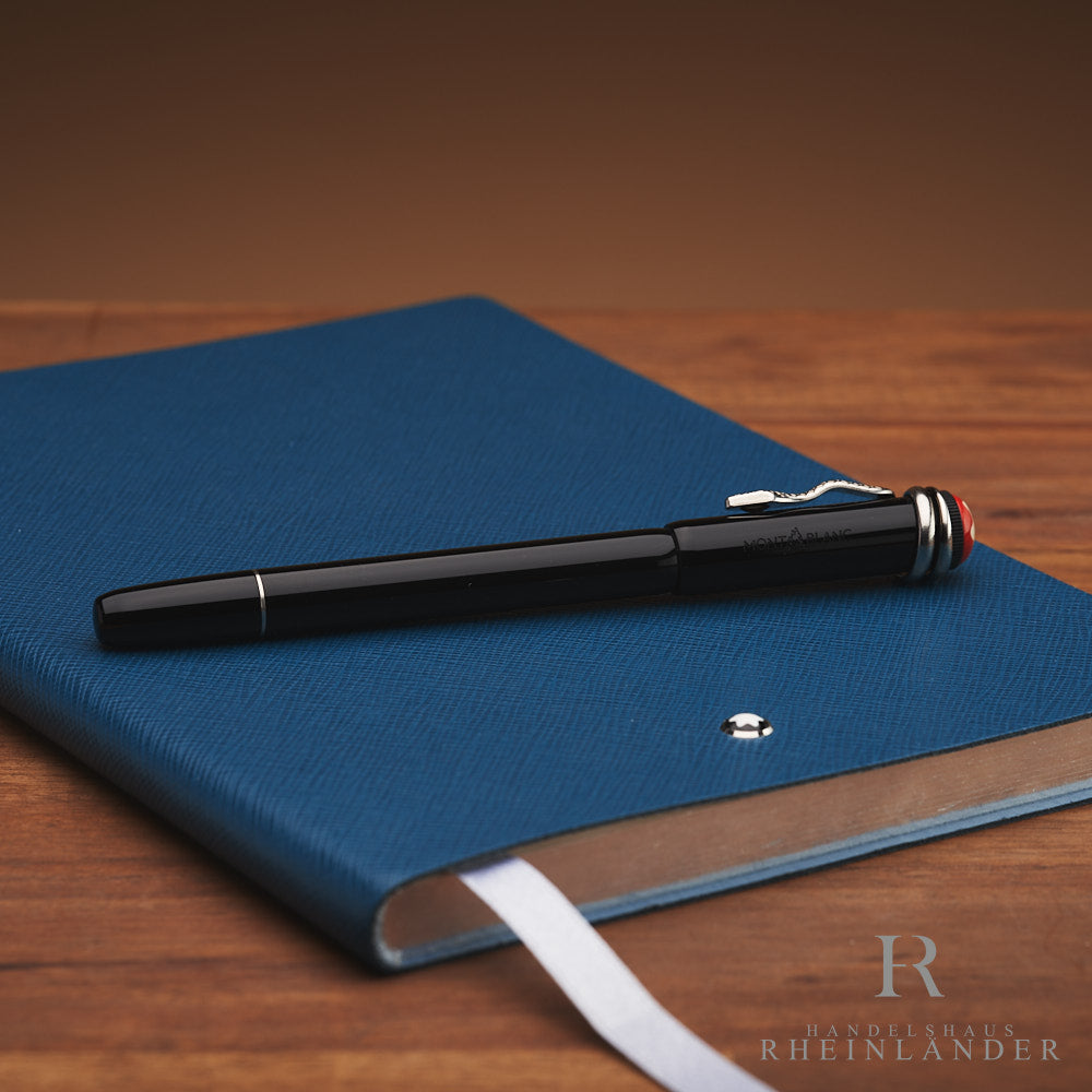 Schwarzer Rollerball mit silbernem Clip in Schlangenform liegt auf blauem Notizbuch