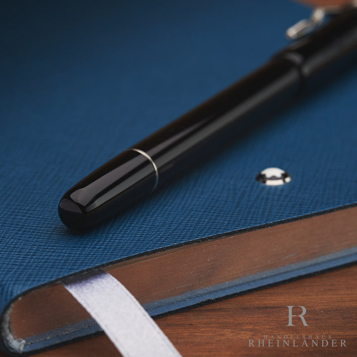 Nahaufnahme vom Schaftende des schwarzen Rollerballs, liegend auf blauem Notizbuch