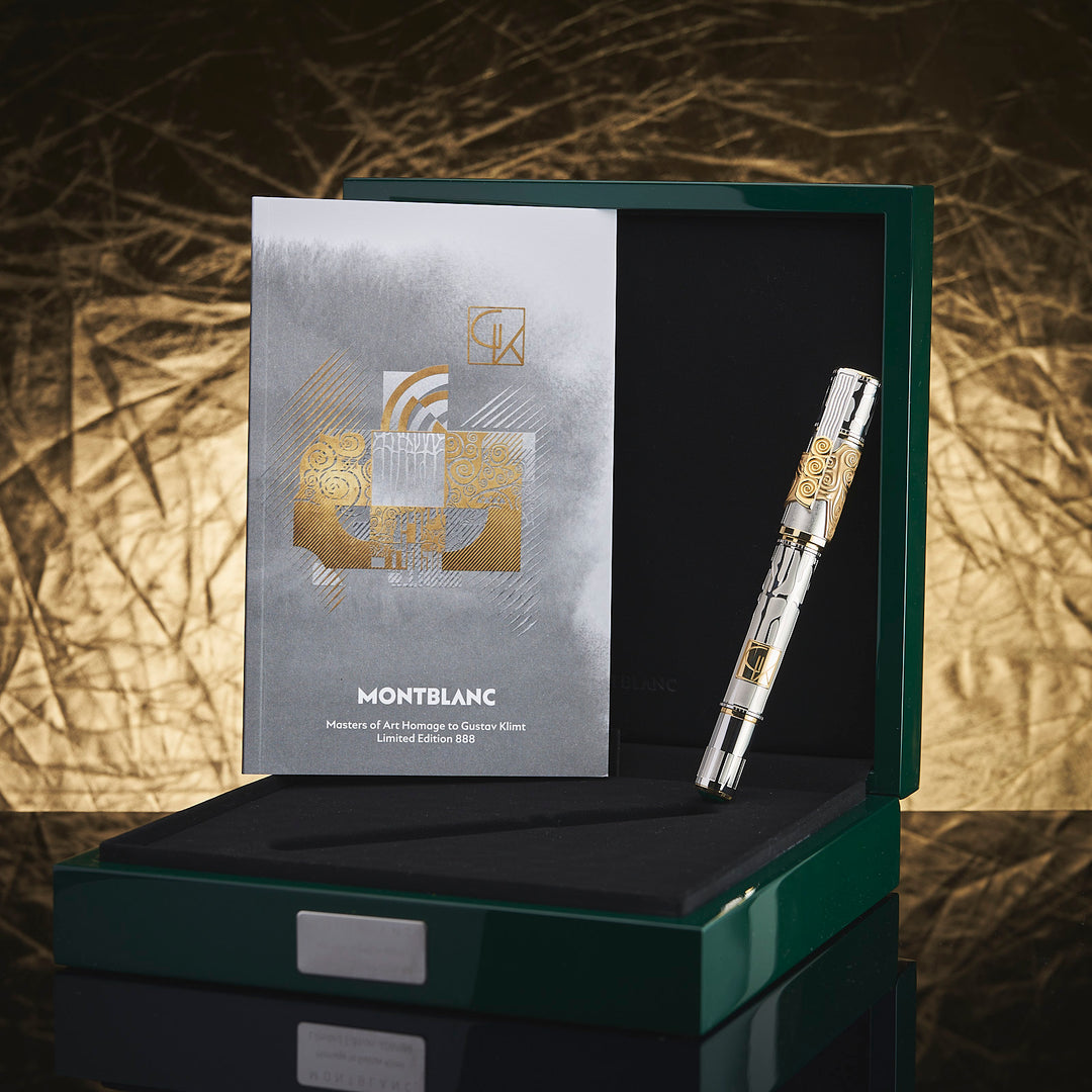 Silber-goldener Füller und Serviceguide lehnen in offener, aussen grün lackierter Originalbox vor goldenem Hintergrund
