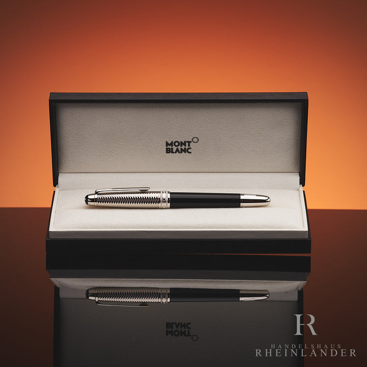 Schwarzer Füller mit silberner, gemusterter Kappe liegt in Originalbox vor orangenem Hintergrund 