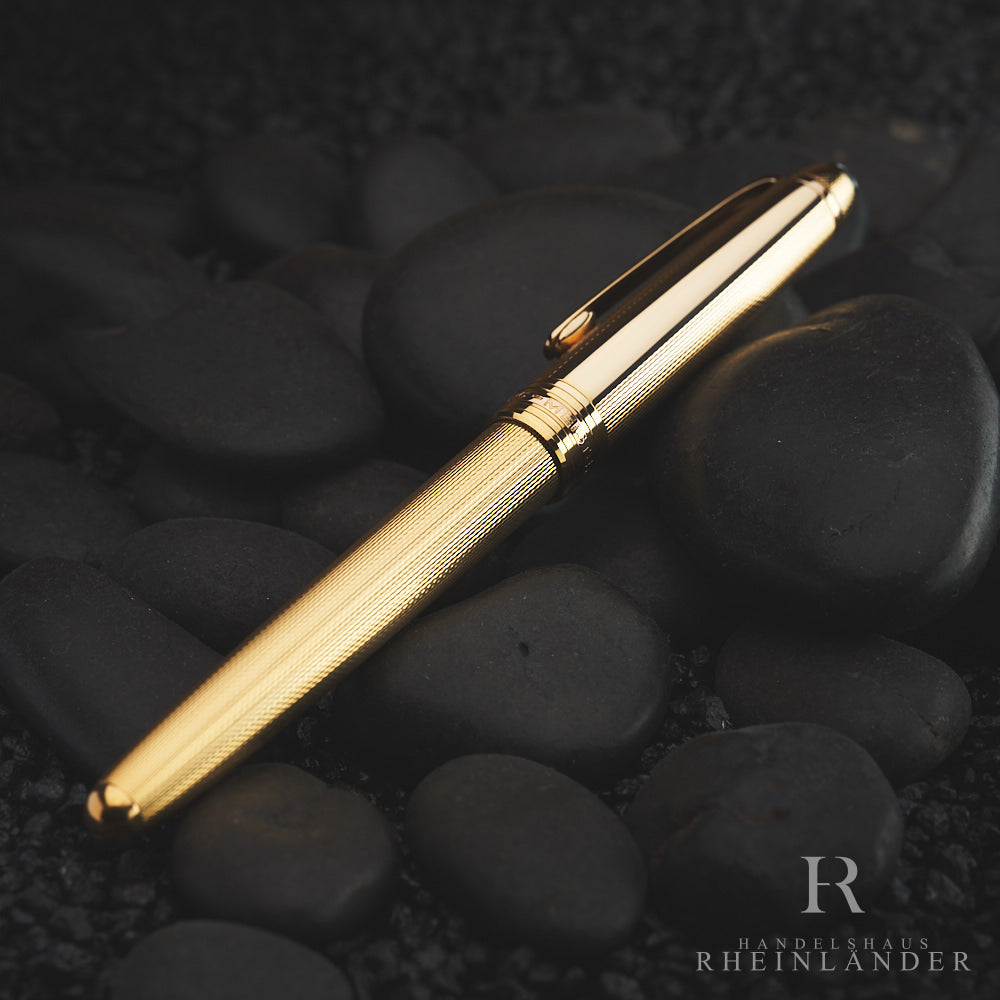 Goldener Füller von schräg oben auf dunkelgrauen, edlen Dekorsteinen liegend fotografiert