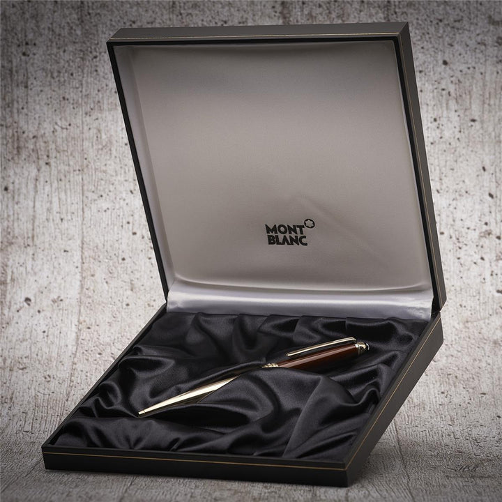 Edler Kugelschreiber in Textilbett der offenen Originalbox liegend fotografiert, Hintergrund hellgrau mit Holzoptik