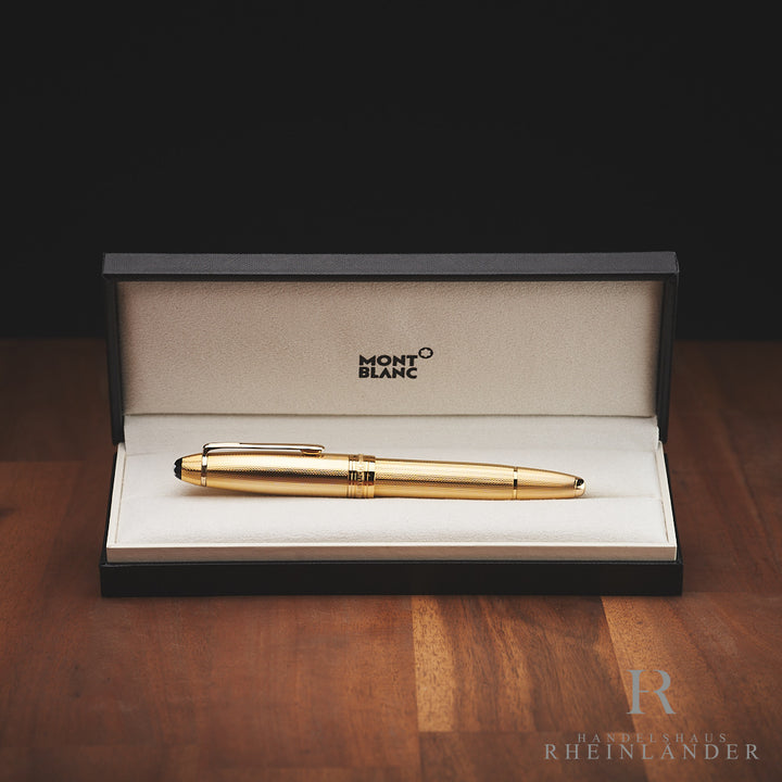 Goldener Füller liegt in offener Originalbox auf Holz-Untergrund vor schwarzem Hintergrund