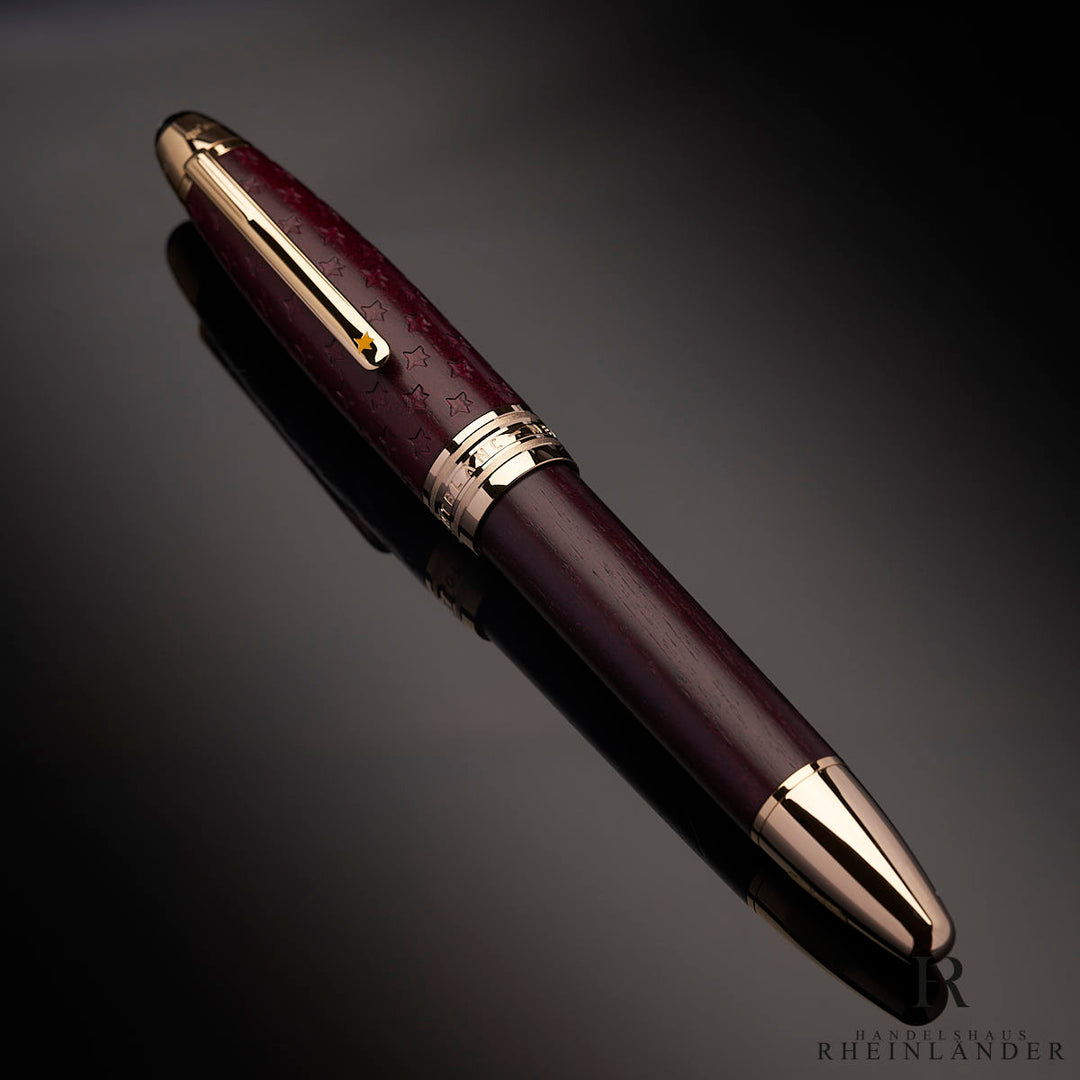 Burgunderfarbener Rollerball mit goldenen Beschlägen von schräg oben vor dunkelgrauem Hintergrund fotografiert