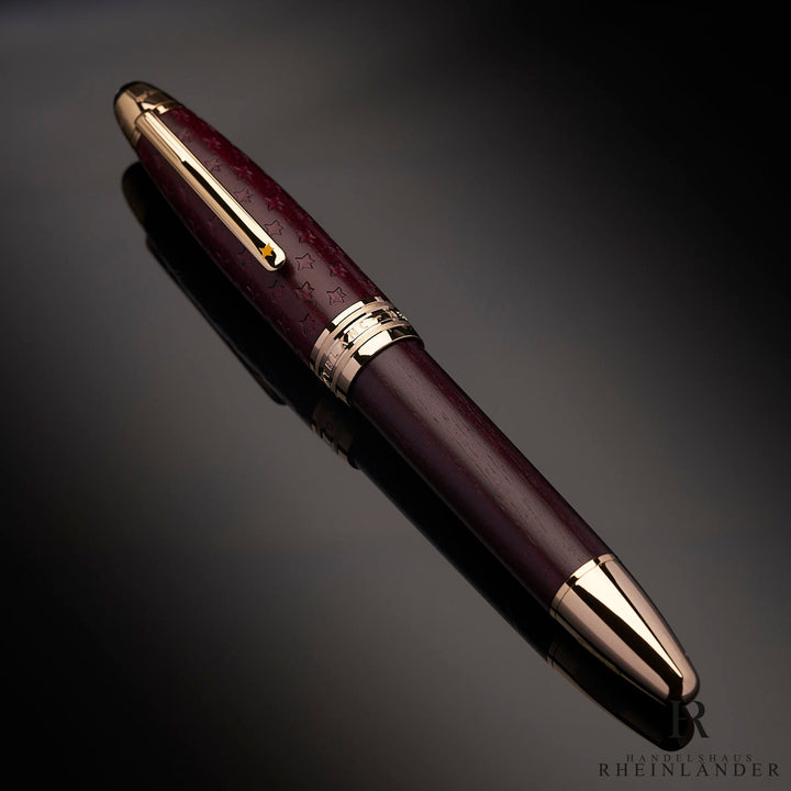 Burgunderfarbener Rollerball mit goldenen Beschlägen von schräg oben vor dunkelgrauem Hintergrund fotografiert