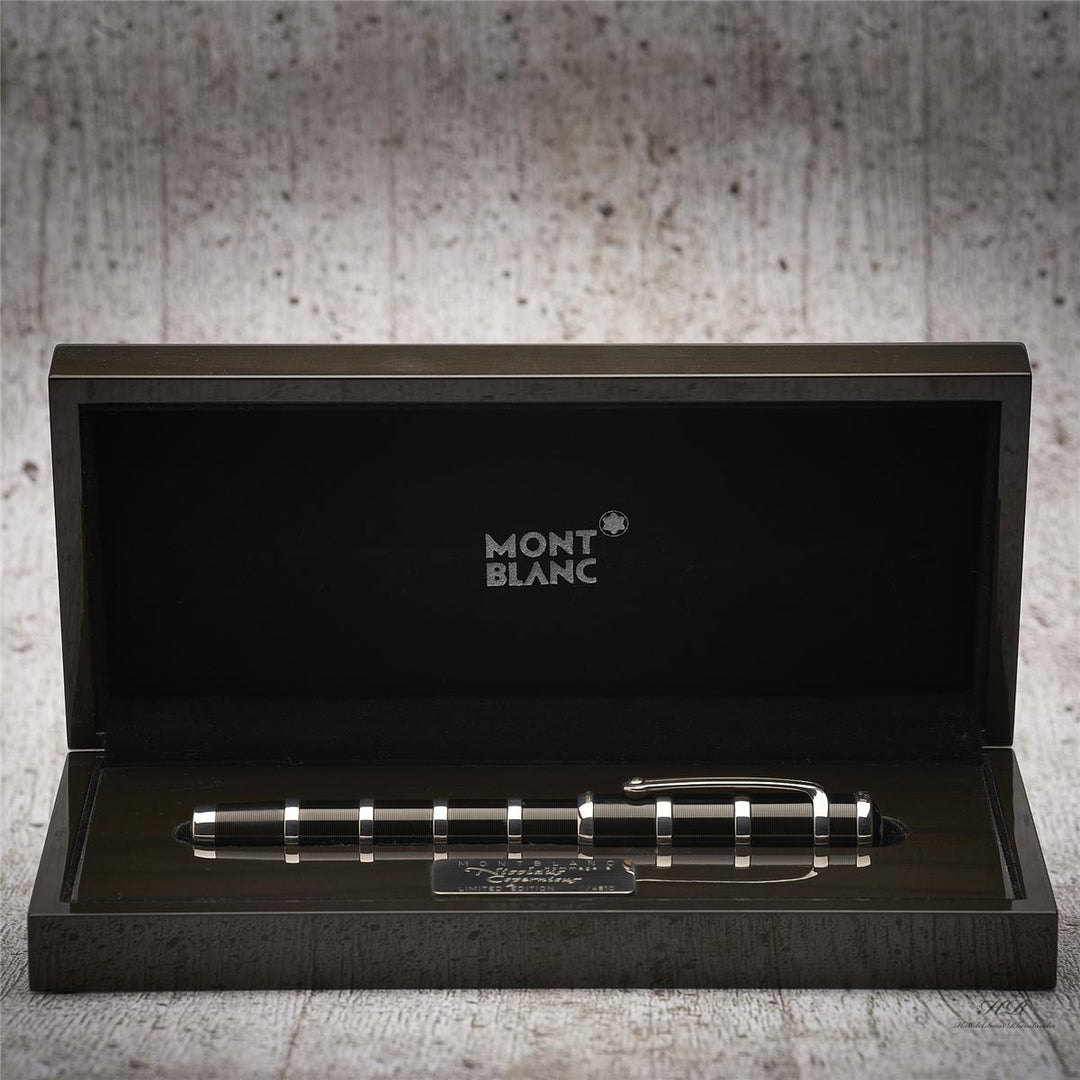 Silber-schwarzer Füller liegt in offener Originalbox vor grauem Hintergrund in Holzoptik