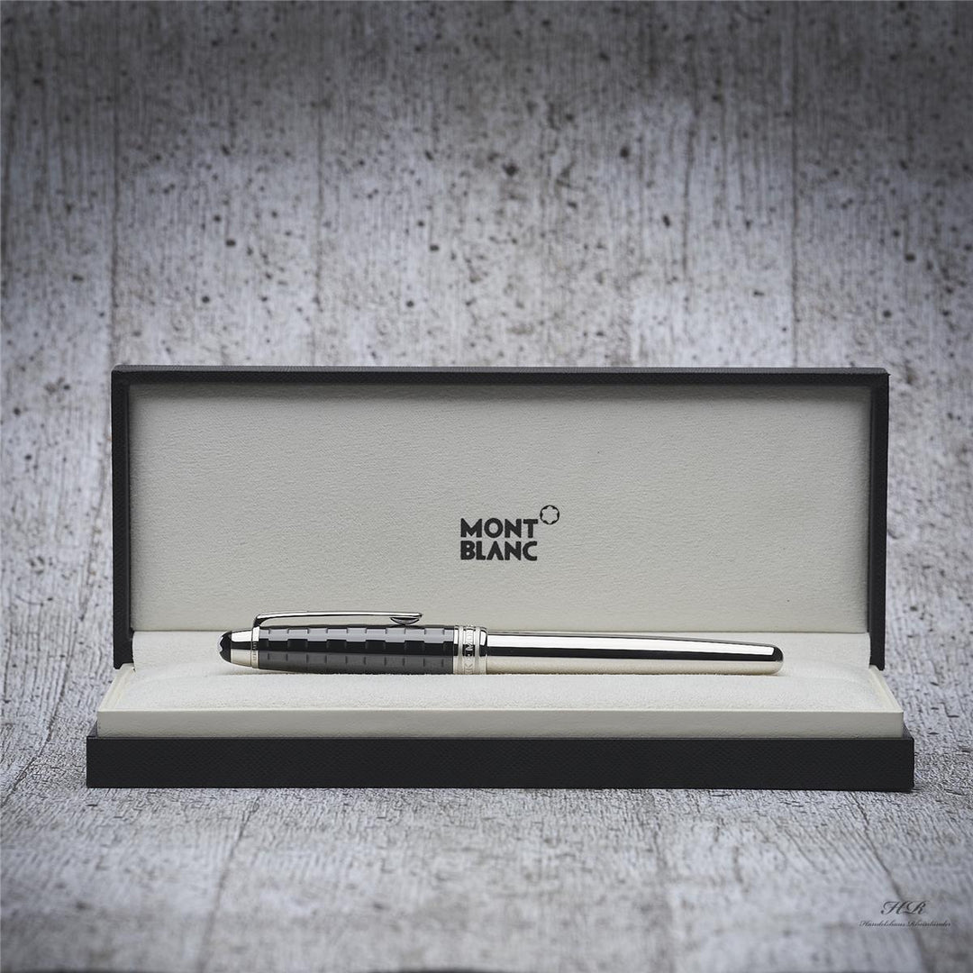 Silberner Füller mit schwarzer Kappe in offener Originalbox liegend fotografiert, Hintergrund hellgrau mit Holzoptik