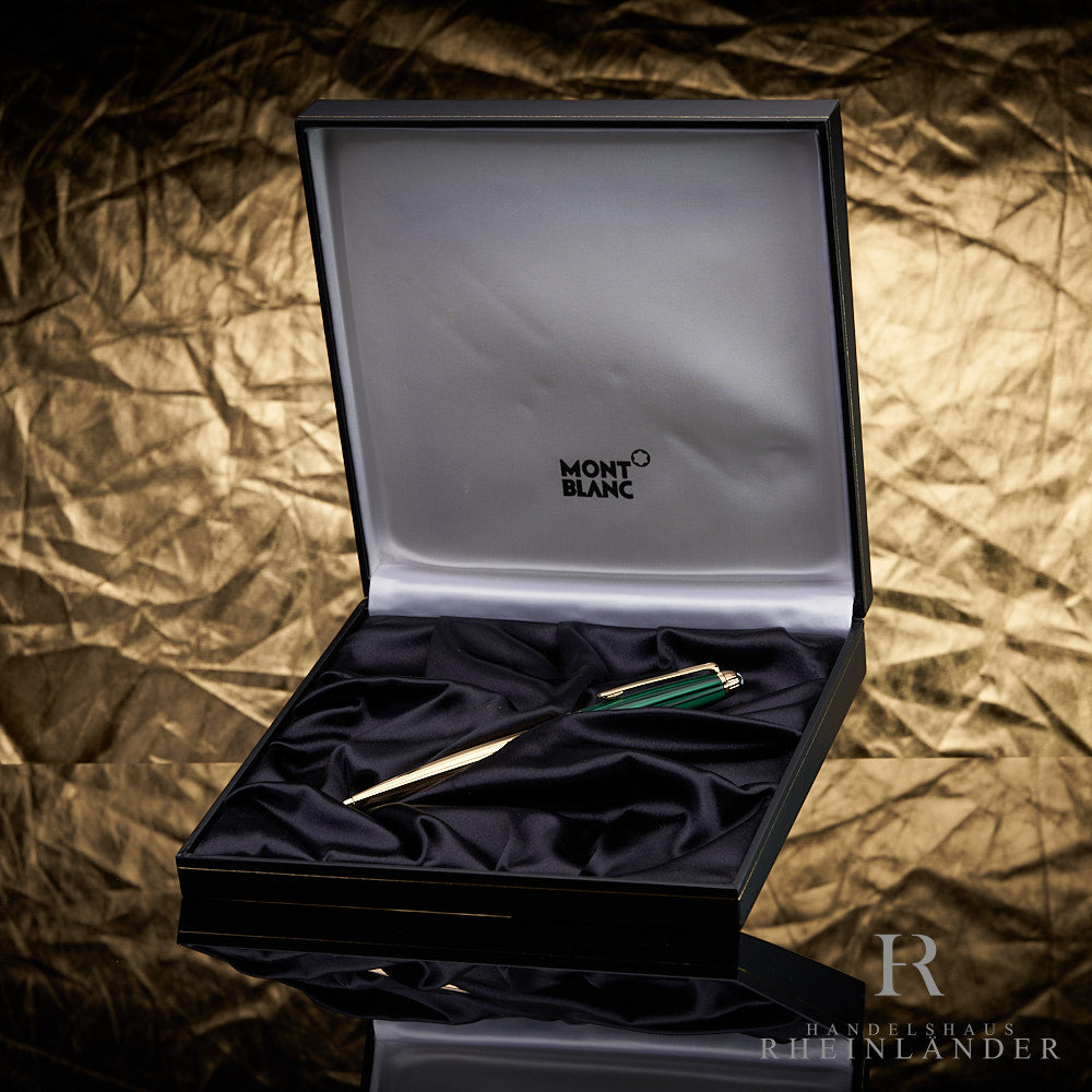 Goldener Stift mit grüner Kappe in offener Originalbox liegend vor goldenem Knitteroptik-Hintergrund