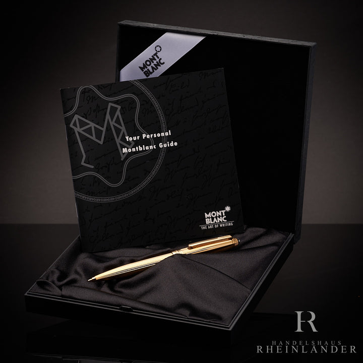 Goldener Bleistift liegt in Originalbox, ebenfalls darin aufgestellt der Serviceguide. Hintergrund ist dunkelgrau.